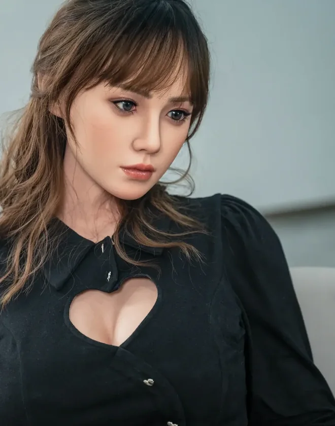 Close-up of a realistic doll face with soft bangs and a black blouse